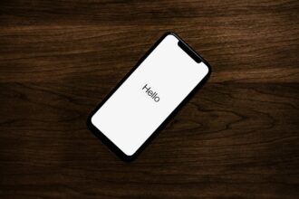 Muutoin tyhjän pöydän päällä puhelin jonka ruudussa teksti "Hello"- Kuva: Taylor Lastovich/unsplash