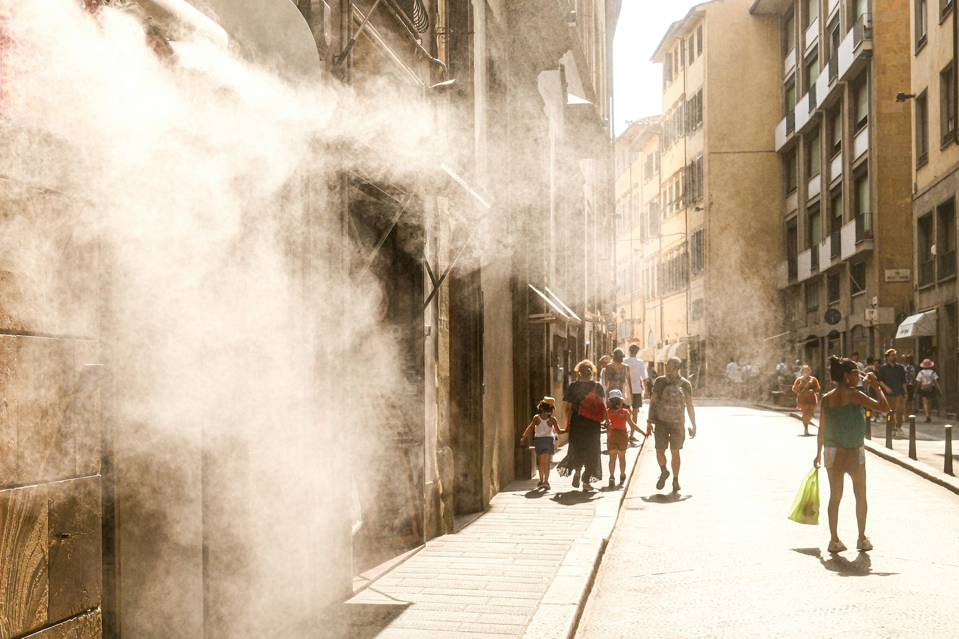Ihmisiä viileän vesihöyryn avulla kuumuutta kestämässä Firenzen kadulla. Kuva: Richard Vanlerberghe/Unsplash. Kuvituskuva