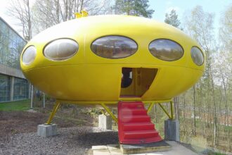 Keltainen Matti Suurosen suunnittelema Futuro-talo, jonka pyöreä muoto ja ovaalit ikkunat muistuttavat lentävää lautasta. Kuva: TTKK / Wikimedia Commons / CC BY-SA 3.0
