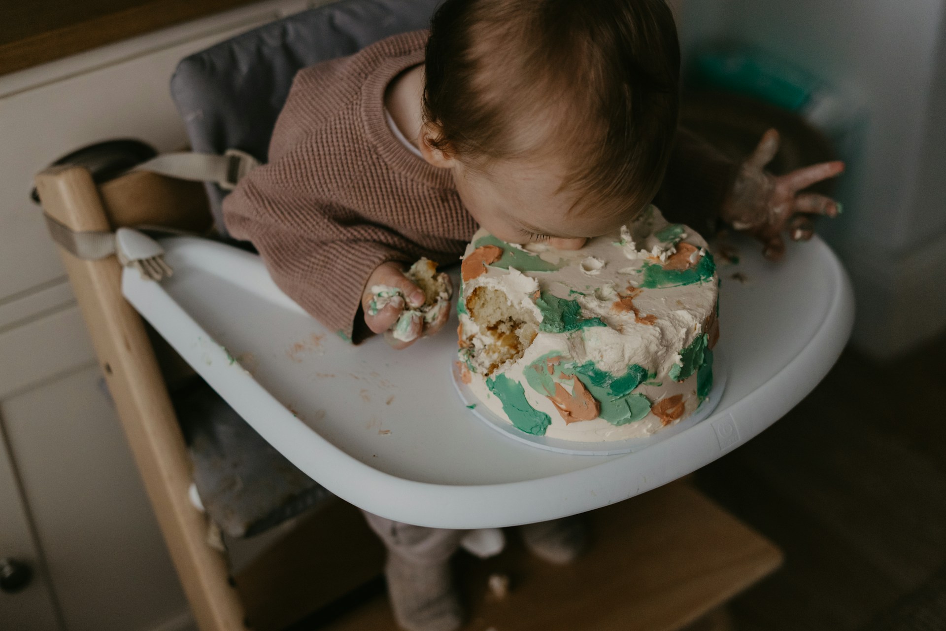 Pieni lapsi syö täytekakkua syöttötuolissa. Kuva: Toa Heftiba / Unsplash