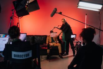 Elokuva- ja videotuotannon kuvausryhmä työskentelee studiossa kameran, mikrofonin ja kuvausvalojen ympäröimänä.