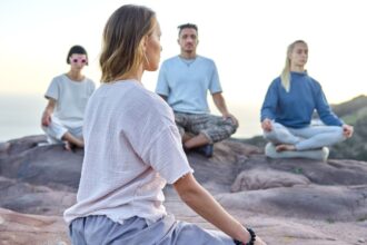 Neljä ihmistä meditoi yhdessä ulkona kallioisessa maisemassa. Kuva: ArtHouse Studio / Pexels