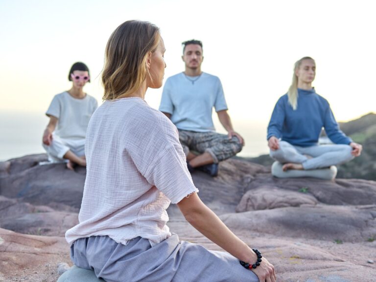 Neljä ihmistä meditoi yhdessä ulkona kallioisessa maisemassa. Kuva: ArtHouse Studio / Pexels