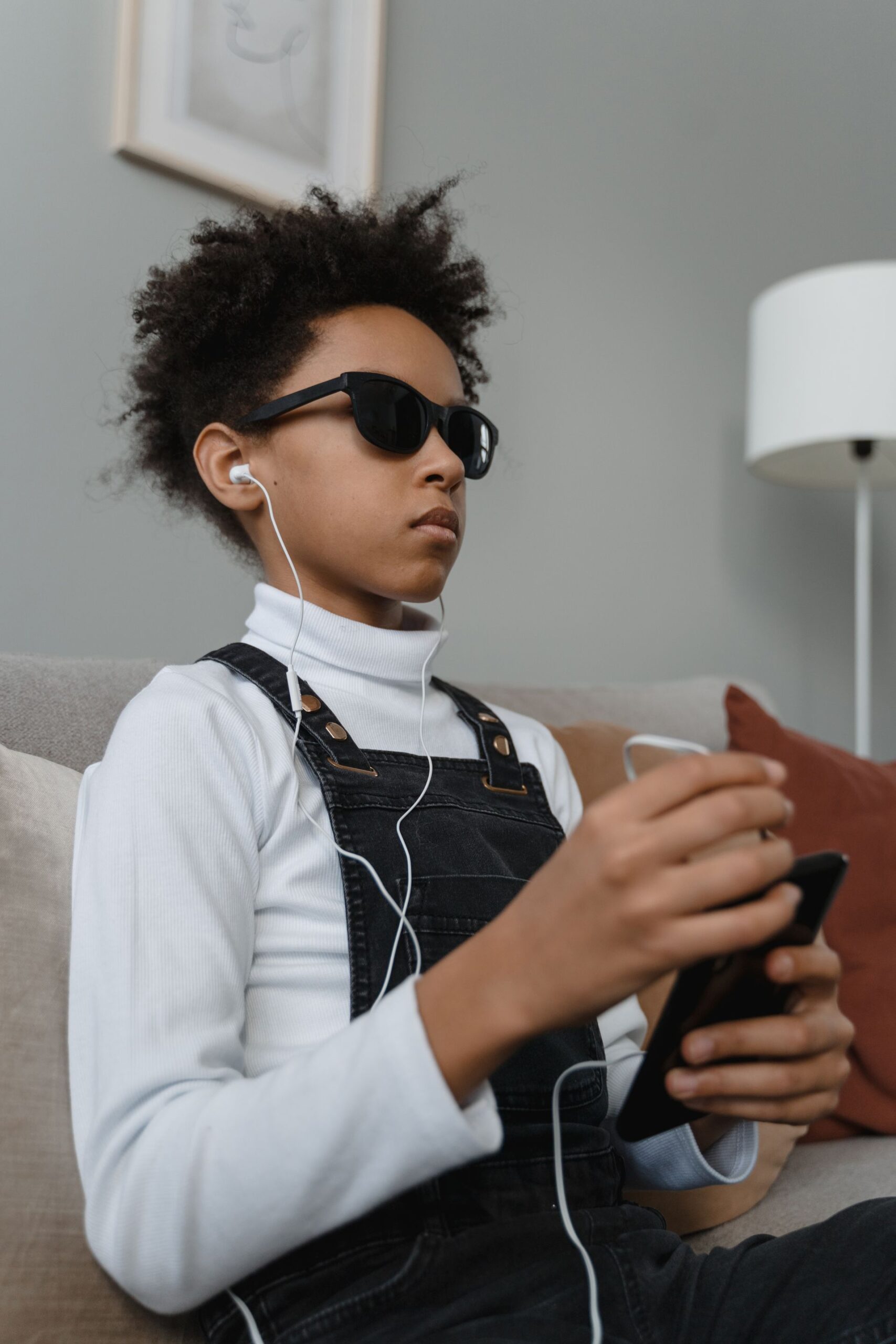 Näkövammainen nuori käyttää älypuhelinta kuulokkeet korvillaan. Kuva: Tima Miroshnichenko / Pexels