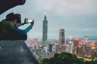 Matkailija kuvaa Taipei 101 -pilvenpiirtäjää älypuhelimella Taiwanissa. Kuva: Vernon Raineil Cenzon/Unsplash