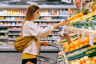 Nainen ruokakaupan hedelmä- ja vihannestiskillä valikoimassa ostoksia. Kuva: Shvetsa/Pexels. Kuvituskuva
