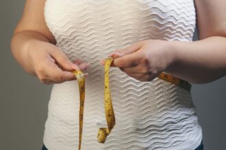 Henkilö mittaa vyötärönympärystään