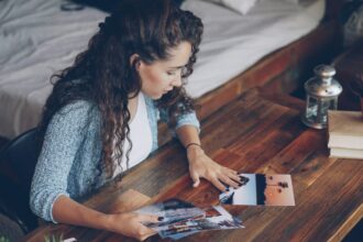 Nuori nainen katselee pöydälle levitettyjä valokuvia. Kuvaaja on Vitaly Gariev / Unsplash