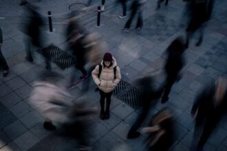 Yksin seisova ihminen keskellä kiireistä ja liikkeessä olevaa ihmisjoukkoa. Kuva: Damla Karaağaçlı / Pexels