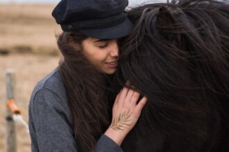 Nainen halaa mustaa hevosta läheisessä hetkessä ulkona. Kuva: ArtHouse Studio / Pexels. Kuvituskuva