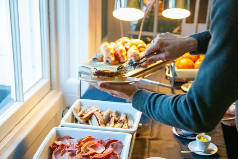 Hotellivieras kokoaa aamiaista runsaasta buffetista, jossa on lämpimiä ruokia, leivonnaisia ja hedelmiä.