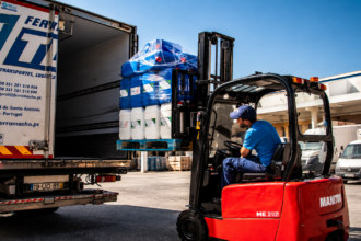 Trukki lastaa kuormalavoille pakattua tavaraa kuorma-autoon logistiikka-alueella.