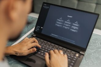 Henkilö kirjoittaa kannettavalla tietokoneella, jonka näytöllä näkyy ChatGPT..