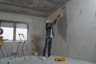 Henkilö maalaa sisäseinää maalitelalla remontin aikana.