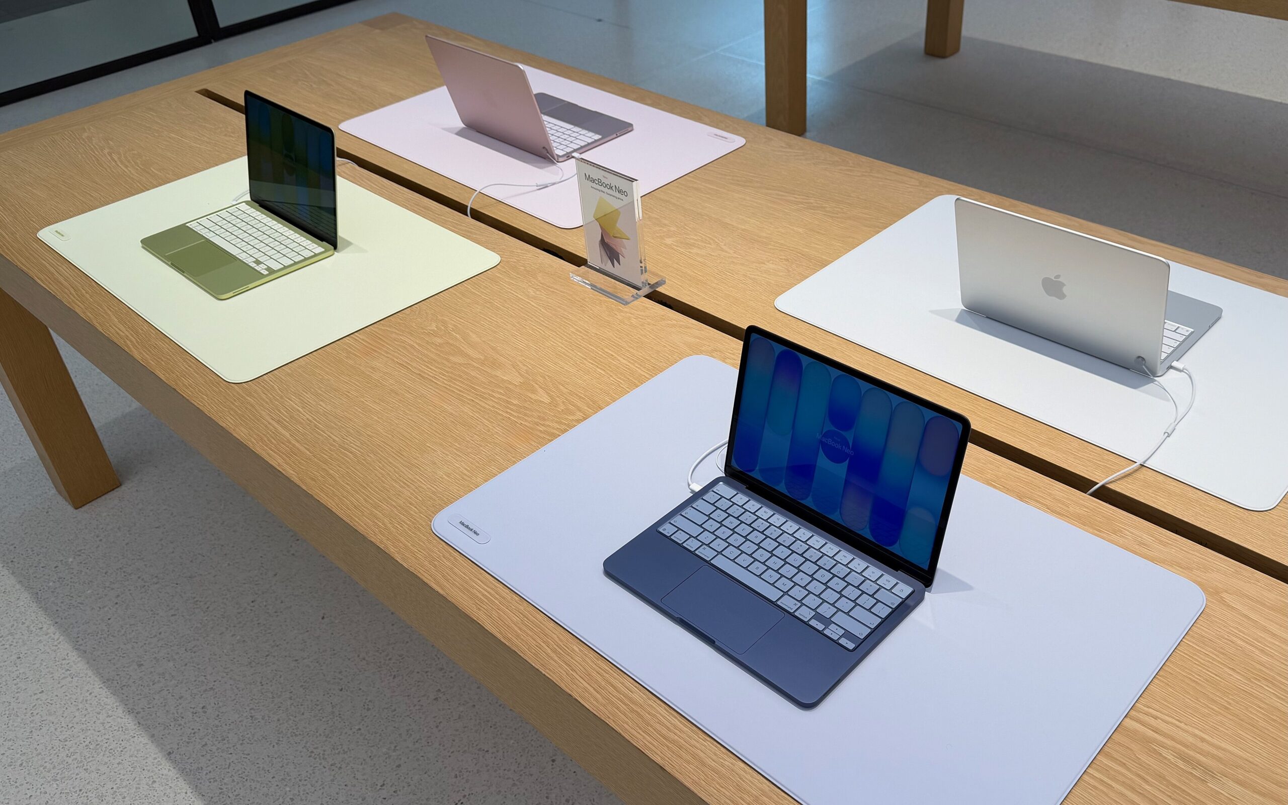 Useita Apple MacBook Neo -kannettavia tietokoneita esillä vierekkäin eri väreissä.